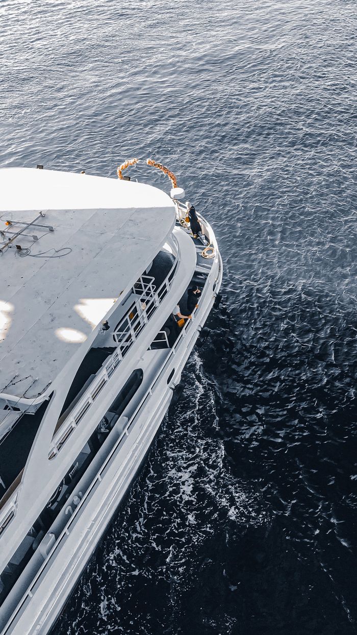 High angle view of a white passenger ship sailing through deep blue waters, showcasing luxury travel.